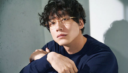 Man wearing glasses and a dark blue shirt against a light background