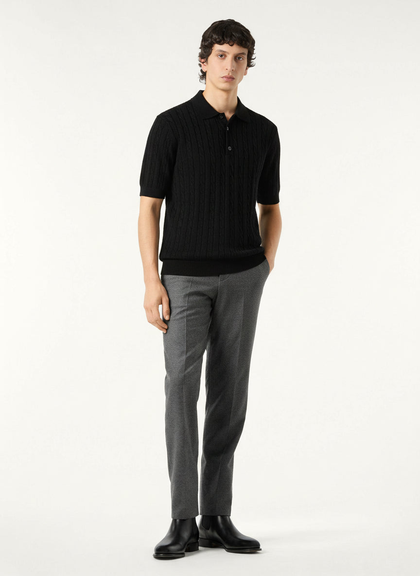 Man wearing a black polo shirt and gray pants on a white background