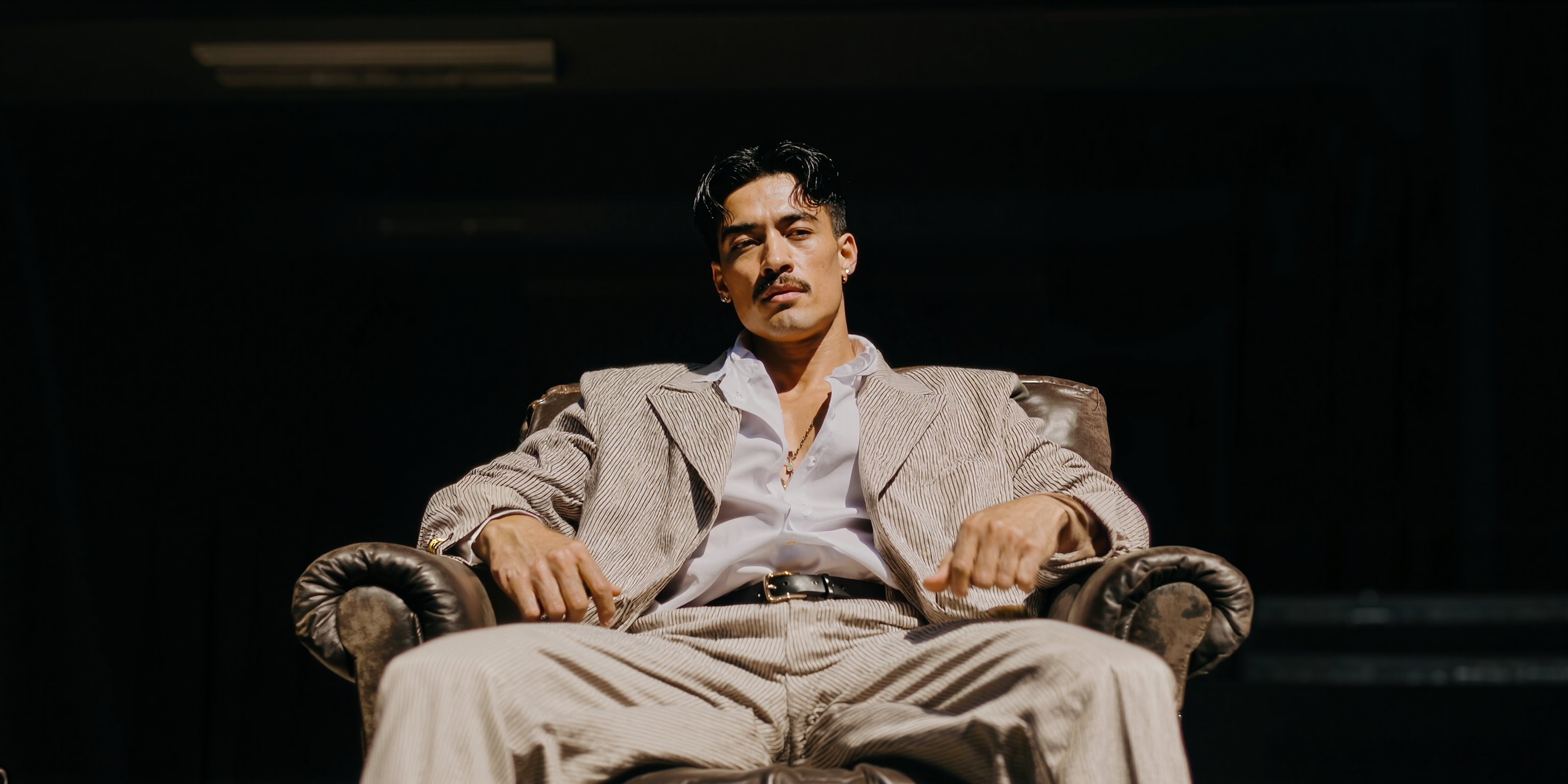 Man sitting in a chair against a dark background